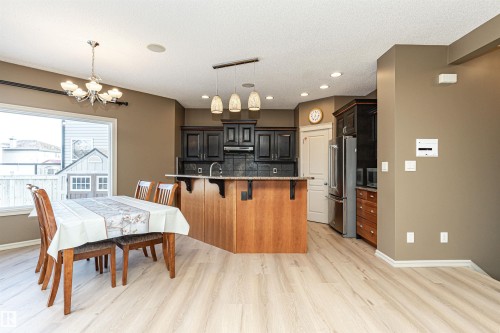 Kitchen with a kitchen breakfast bar, a chandelier, high quality fridge, pendant lighting, and light wood-style flooring - 1612 Lacombe Crest, Edmonton, AB - Indoor Photo Showing Dining Room