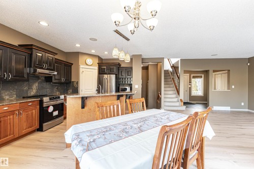 Dining space with stairway, light wood-style floors, a chandelier, a textured ceiling, and recessed lighting - 1612 Lacombe Crest, Edmonton, AB - Indoor