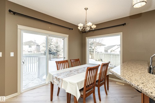Dining room featuring healthy amount of natural light, a chandelier, a textured ceiling, and light wood-type flooring - 1612 Lacombe Crest, Edmonton, AB - Indoor Photo Showing Dining Room
