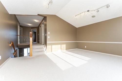 Unfurnished room featuring lofted ceiling, carpet flooring, track lighting, and a textured ceiling - 1612 Lacombe Crest, Edmonton, AB - Indoor Photo Showing Other Room
