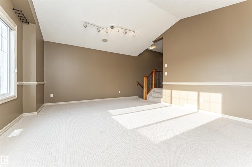 Carpeted empty room featuring vaulted ceiling, stairway, and a textured ceiling - 1612 Lacombe Crest, Edmonton, AB - Indoor Photo Showing Other Room