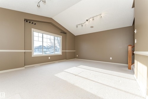 Spare room with track lighting, vaulted ceiling, a textured ceiling, and carpet flooring - 1612 Lacombe Crest, Edmonton, AB - Indoor Photo Showing Other Room