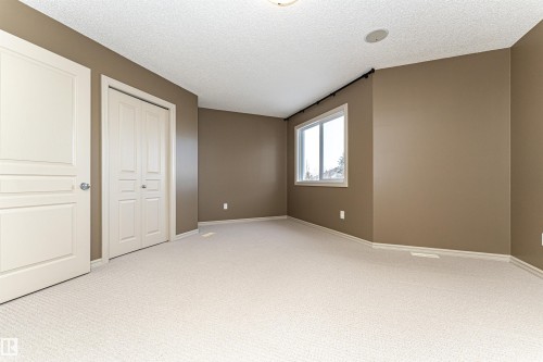 Unfurnished bedroom with light colored carpet, a textured ceiling, and a closet - 1612 Lacombe Crest, Edmonton, AB - Indoor Photo Showing Other Room