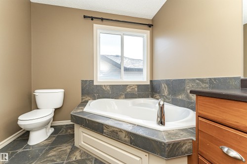 Full bathroom featuring a garden tub, a textured ceiling, vanity, and dark marble finish flooring - 1612 Lacombe Crest, Edmonton, AB - Indoor Photo Showing Bathroom