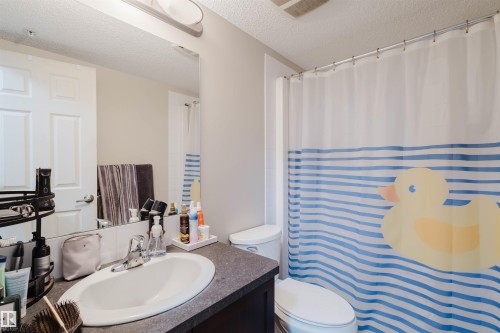Full bath featuring vanity, a shower with shower curtain, and a textured ceiling - 108 396 Silver Berry Road, Edmonton, AB - Indoor Photo Showing Bathroom