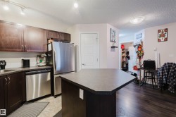 Kitchen featuring dark countertops, appliances with stainless steel finishes, a center island, dark brown cabinetry, and a textured ceiling - 