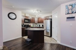Kitchen featuring dark brown cabinetry, black appliances, a center island, dark wood-type flooring, and a textured ceiling - 