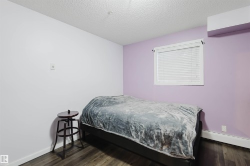 Bedroom featuring a textured ceiling, a baseboard heating unit, and dark wood-style flooring - 108 396 Silver Berry Road, Edmonton, AB - Indoor Photo Showing Bedroom