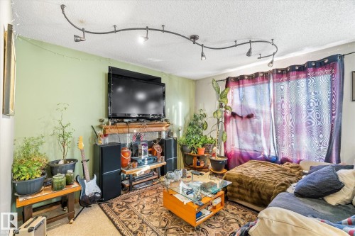 Carpeted living room with a textured ceiling and rail lighting - 15035 133 Street, Edmonton, AB - Indoor Photo Showing Living Room With Fireplace