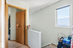 Hallway with an upstairs landing, carpet floors, and a textured ceiling - 