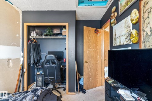 Carpeted bedroom featuring a textured ceiling, a closet, and an office area - 15035 133 Street, Edmonton, AB - Indoor