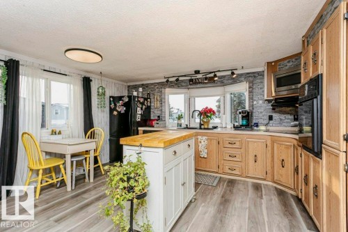 Kitchen with wood counters, light wood-style flooring, black appliances, a textured ceiling, and light brown cabinets - 216 53222 Rge Rd 272, Rural Parkland County, AB - Indoor