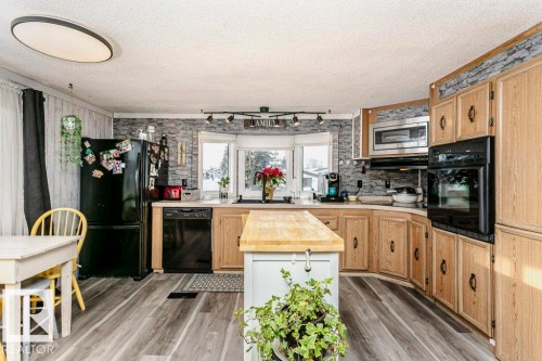 Kitchen featuring wooden counters, light brown cabinetry, black appliances, light wood finished floors, and a textured ceiling - 216 53222 Rge Rd 272, Rural Parkland County, AB - Indoor Photo Showing Kitchen