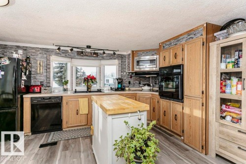 Kitchen with wood counters, black appliances, light brown cabinetry, a textured ceiling, and light wood-type flooring - 216 53222 Rge Rd 272, Rural Parkland County, AB - Indoor Photo Showing Kitchen