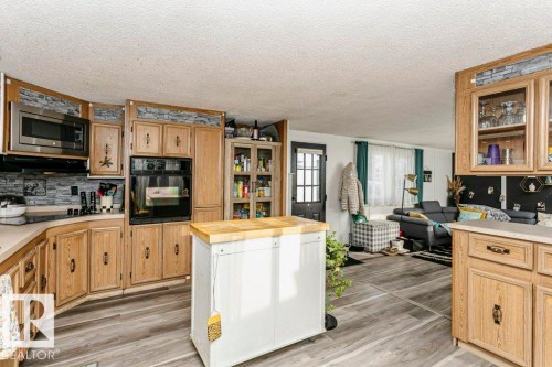 Kitchen featuring black appliances, butcher block counters, light brown cabinets, decorative backsplash, and light wood finished floors - 216 53222 Rge Rd 272, Rural Parkland County, AB - Indoor Photo Showing Kitchen