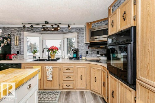 Kitchen with light brown cabinetry, plenty of natural light, black appliances, and a textured ceiling - 216 53222 Rge Rd 272, Rural Parkland County, AB - Indoor Photo Showing Kitchen With Double Sink