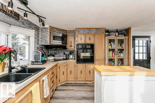 Kitchen with butcher block countertops, black oven, light brown cabinets, stainless steel microwave, and decorative backsplash - 216 53222 Rge Rd 272, Rural Parkland County, AB - Indoor Photo Showing Kitchen With Double Sink