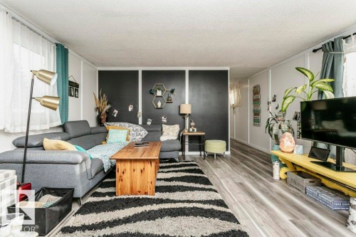 Living room featuring wood finished floors, a textured ceiling, and a decorative wall - 216 53222 Rge Rd 272, Rural Parkland County, AB - Indoor Photo Showing Living Room