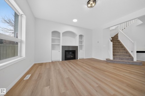 Unfurnished living room featuring built in shelves and stairs - 1741 63A Street, Edmonton, AB 