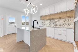 Kitchen with white cabinetry, an island with sink, light stone countertops, decorative light fixtures, and recessed lighting - 