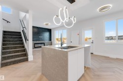 Kitchen featuring plenty of natural light, modern cabinets, a tile fireplace, and pendant lighting - 