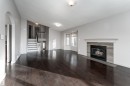 Unfurnished living room featuring lofted ceiling, a tiled fireplace, stairs, dark wood-type flooring, and arched walkways - 174 Oeming Road, Edmonton, AB  - Indoor Photo Showing Living Room With Fireplace 