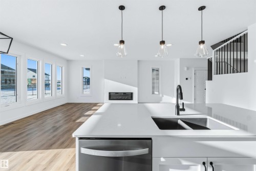 Kitchen with dishwasher, open floor plan, hanging light fixtures, recessed lighting, and light wood-style flooring - 2211 4 Avenue, Edmonton, AB - Indoor Photo Showing Kitchen With Fireplace With Double Sink With Upgraded Kitchen