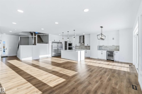 Unfurnished living room featuring light wood-type flooring, beverage cooler, recessed lighting, and a chandelier - 2211 4 Avenue, Edmonton, AB - Indoor Photo Showing Kitchen