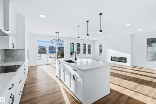 Kitchen featuring white cabinets, hanging light fixtures, open floor plan, wall chimney exhaust hood, and recessed lighting - 2211 4 Avenue, Edmonton, AB - Indoor Photo Showing Kitchen With Upgraded Kitchen