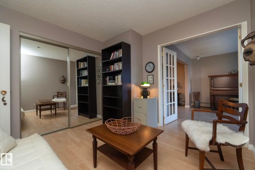 Living room with light wood-type flooring, a textured ceiling, and french doors - 203 10171 119 Street Nw, Edmonton, AB - Indoor