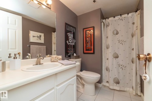 Bathroom featuring a shower with curtain, vanity, and light tile patterned floors - 203 10171 119 Street Nw, Edmonton, AB - Indoor Photo Showing Bathroom