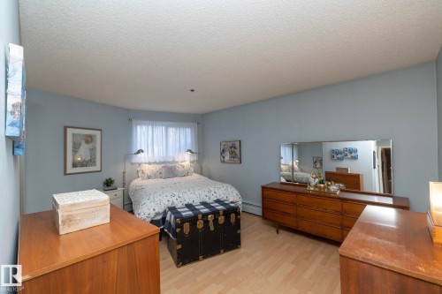 Bedroom featuring a textured ceiling, light wood-style floors, and baseboard heating - 203 10171 119 Street Nw, Edmonton, AB - Indoor Photo Showing Bedroom