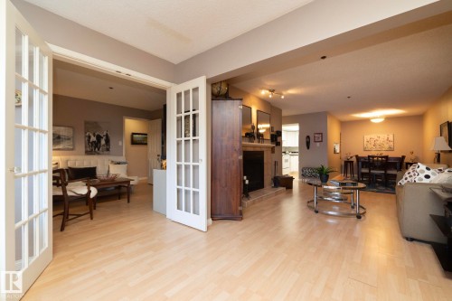 Living area with a fireplace with raised hearth and light wood-style flooring - 203 10171 119 Street Nw, Edmonton, AB - Indoor Photo Showing Other Room