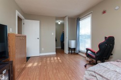 Bedroom with a textured ceiling, light wood finished floors, and a walk in closet - 