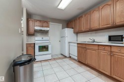 Kitchen featuring white appliances, light countertops, brown cabinets, a textured ceiling, and under cabinet range hood - 