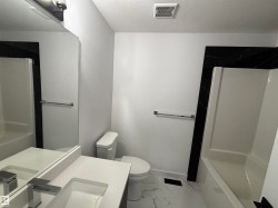 Bathroom with shower / bath combination, vanity, a textured ceiling, and light marble finish flooring - 