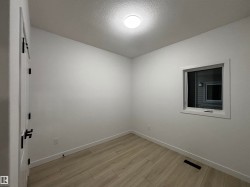 Empty room featuring light wood finished floors and a textured ceiling - 
