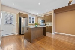 Kitchen with a center island, appliances with stainless steel finishes, light stone counters, light wood finished floors, and modern cabinets - 