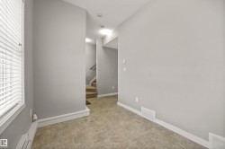 Empty room featuring stairs, a baseboard heating unit, and a textured ceiling - 
