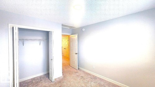 Unfurnished bedroom with a textured ceiling, carpet, and a closet - 4610 Kinsella Landing Sw, Edmonton, AB - Indoor