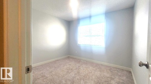 Carpeted spare room featuring a textured ceiling and baseboards - 4610 Kinsella Landing Sw, Edmonton, AB - Indoor Photo Showing Other Room