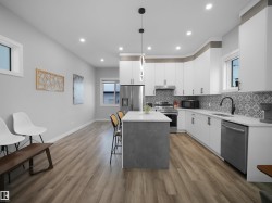 Kitchen with white cabinets, decorative light fixtures, stainless steel appliances, a center island, and recessed lighting - 