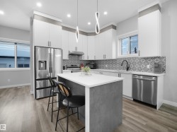 Kitchen featuring white cabinetry, appliances with stainless steel finishes, a center island, a kitchen bar, and light wood-style floors - 