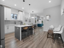 Kitchen featuring white cabinets, a kitchen breakfast bar, decorative light fixtures, a kitchen island, and light wood-style floors - 