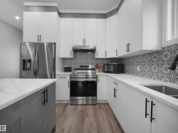 Kitchen with appliances with stainless steel finishes, white cabinets, light wood finished floors, light stone countertops, and recessed lighting - 