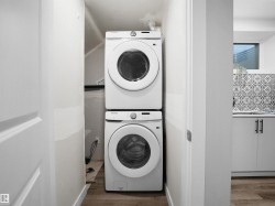 Laundry room with stacked washer / dryer and wood finished floors - 