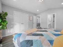 Bedroom with a closet, lofted ceiling, connected bathroom, wood finished floors, and recessed lighting - 