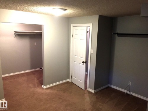 Unfurnished bedroom with dark colored carpet, a textured ceiling, and a closet - 2928 49A Street, Edmonton, AB - Indoor Photo Showing Other Room