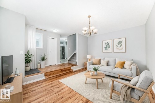 Living area featuring light wood-type flooring, a chandelier, and stairway - 2928 49A Street, Edmonton, AB - Indoor Photo Showing Living Room