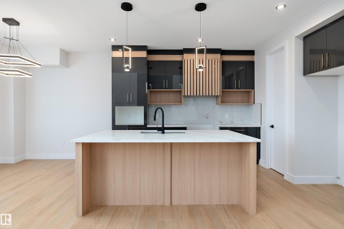 Kitchen featuring light stone counters, hanging light fixtures, a center island with sink, light wood-style flooring, and backsplash - 38 Astoria Place, Devon, AB - Indoor Photo Showing Kitchen